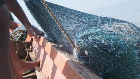 Indian Fishermen pulling blue fishing net full of fish and shrimp out of the sea slow motion