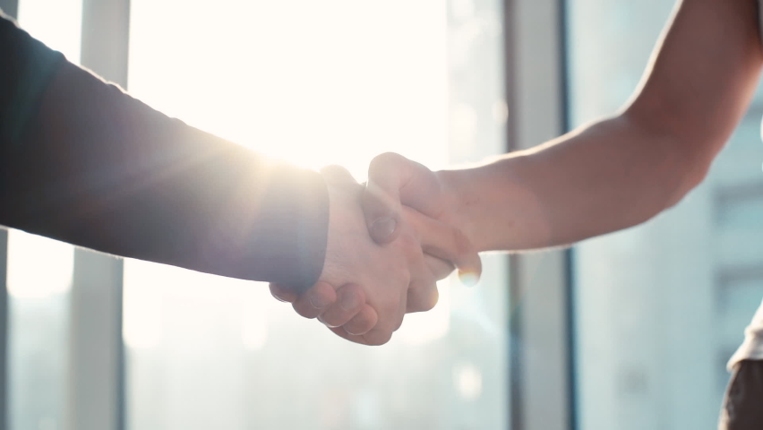Close-up of two colleagues shaking hands in the office against the background of a window and sunbeam. Tracking shot in slow motion. | Shutterstock HD Video #1061344135