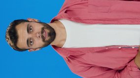 Portrait of young caucasian man in his 20s on blue background in studio. Beautiful handsome man wearing sunglasses.Slow motion 4K video. Blue background.Video for the vertical story.
