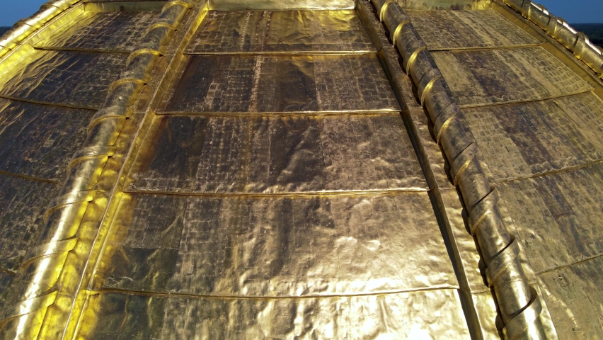 Drone aerial footage panning up from gold dome and circling spire of Iowa State Capitol with view of downtown in Des Moines, Iowa