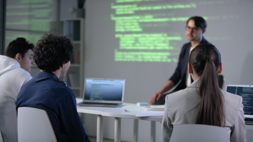 Male pupil raising hand in computer class during IT lesson asking teacher details of computer programming and program coding Royalty-Free Stock Footage #1061349304