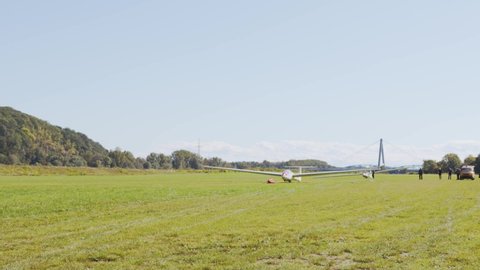 Small white glider gets pulled by long rope winch take off from ground in small airport. Flying gliders as hobby, graceful and expensive small private airplane.