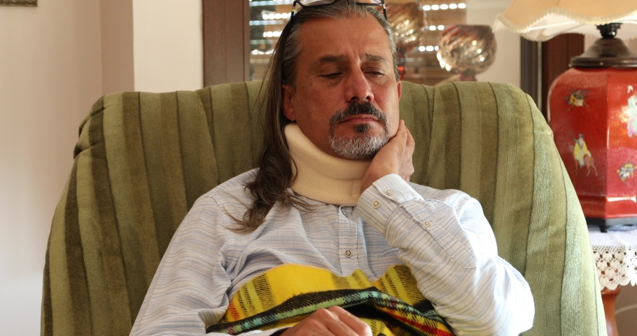 Portrait of a poor middle aged man with a neck brace sitting on sofa Royalty-Free Stock Footage #1061354842