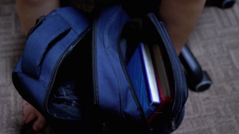 Schoolboy Hands Collect Books in a Backpack. A child collects a briefcase to school. Child is Preparing to Go to School. Training. Getting knowledge at school. Education concept. 4K.
