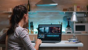 Video editor working from home at night at new project editing audio film montage sitting in modern kitchen. Content creator using professional laptop modern technology network wireless