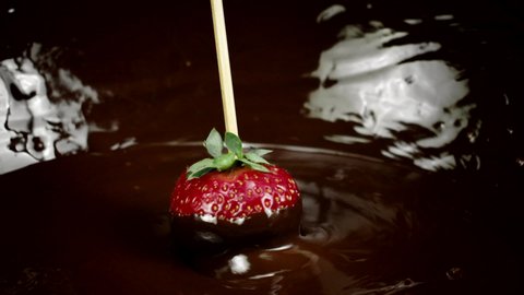juicy red ripe strawberry berry rotating being covered with chocolate slow mo. chocolate-covered strawberries. Cooking delicious chocolate desserts. Advertising for handcrafted confectionary shop