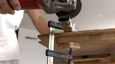 A electric hacksaw is cutting a metal rod on a wooden workbench