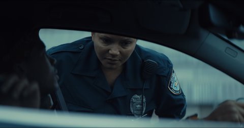 African-American black driver getting a ticket from mixed-raced female police officer. Shot on RED cinema camera with 2x Anamorphic lens