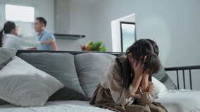 Asian girl kid sitting and crying on bed while parents having fighting or quarrel conflict at home. Child covering face and eyes with hands do not want to see the violence. Domestic problem in family. - Powered by Shutterstock - Get 15% off with code: PIKWIZARD15