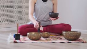 Woman playing on Tibetan singing bowl while sitting on yoga mat. Vintage tonned. stock footage. Slow Motion video. Close up