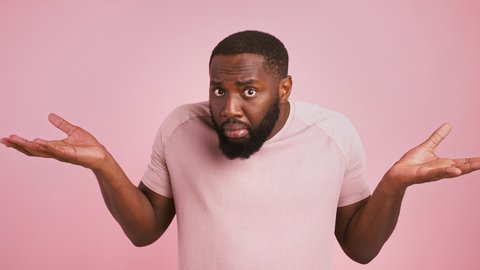 So what. African american man raising his hands, waiting for excusement, pink studio background