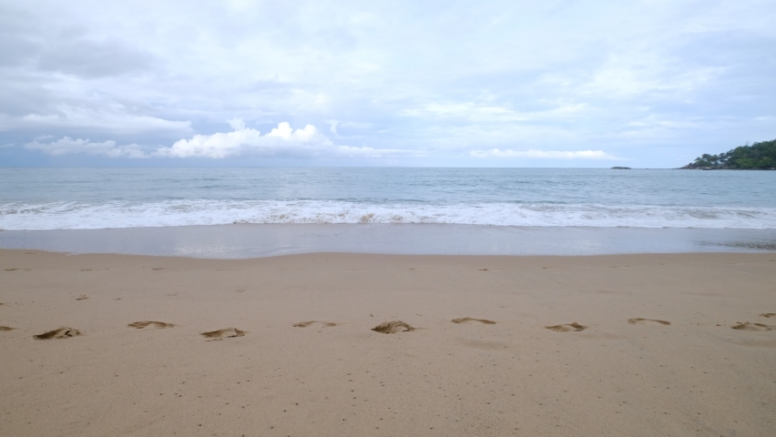 Footprints on the sandy beach. The sand and soft waves in the morning