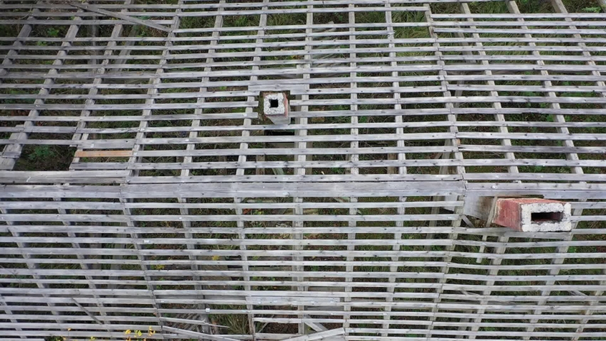 Drone view of remains of roof of an abandoned building, wooden frame of the building without roofing material, top view