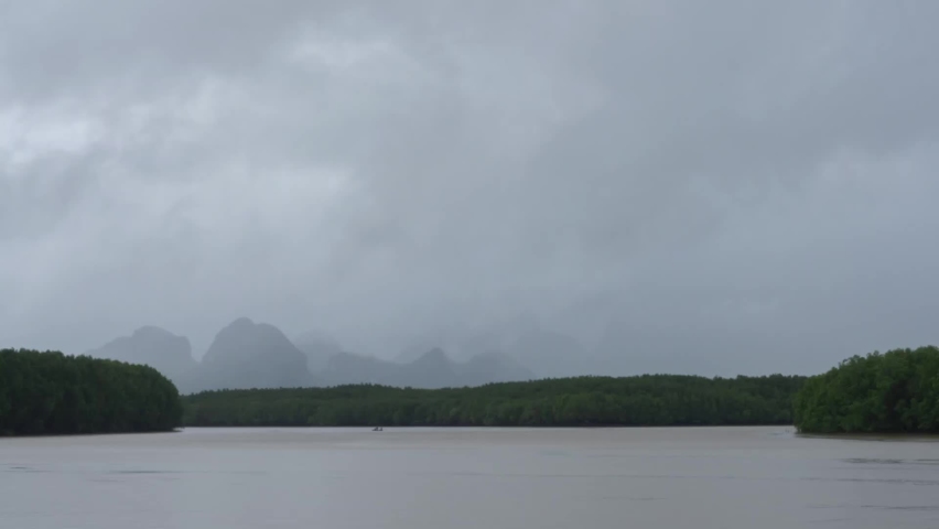 lake and mountain view in cloudy day, stormy dramatic sky in rainy season. wind blow clouds moving b-roll horizontal above river in topical country,