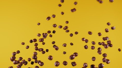 Chocolate corn cereal balls moving up and down on a yellow background.