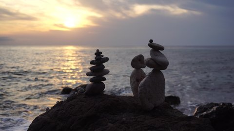 Balanced pebble pyramid on the beach on a sunny day. Abstract Sea bokeh from sunset on background. Selective focus. Zen stones on the sea beach, meditation, spa, harmony, calmness, balance concept