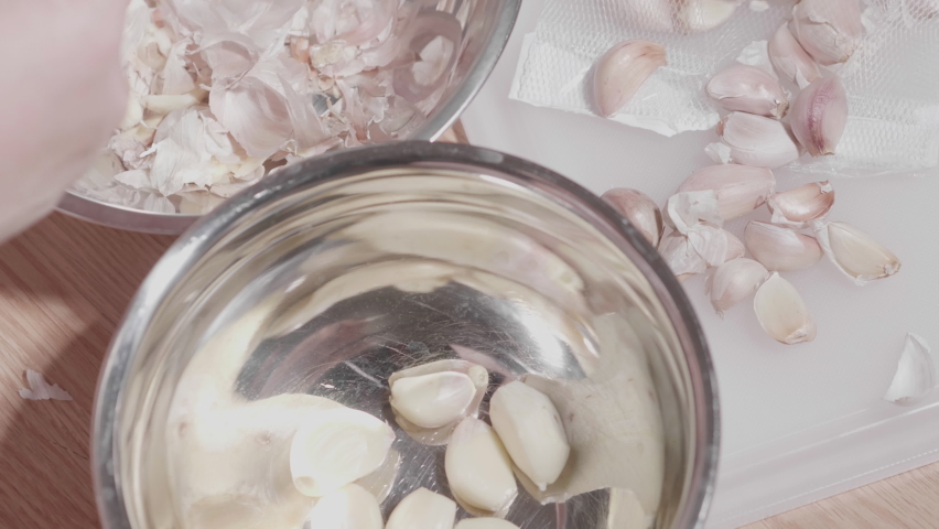 Slow motion close up woman hand knife peeling off garlic for prepare ingredient food. Housewife cooking at home for social distancing avoid eat at outside home restaurant new normal coronavirus crisis