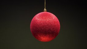 Red New year ball toy rotates clockwise  shining and luminating the light. Christmas and New Year decoration isolated on dark green background.  - Powered by Shutterstock - Get 15% off with code: PIKWIZARD15
