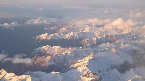 Flight over the Italian and Swiss Alps. Incredibly beautiful landscape, snow-capped mountain peaks in the rays of the setting sun.