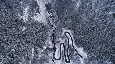 Aerial drone 4K footage of a curved windy road motorway through mountains next to a river in winter landscape in Romania - Bicaz Gorges