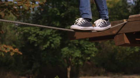 Close-up of a little boy walking on a tightrope in a rope Park, close-up of his feet in sneakers.