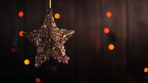 Golden Christmas star with colorful stones on a wooden background with flashing lights. Copy space. Bokeh. Star abstract decoration lights, multicolored sparkles, shine blurred background.