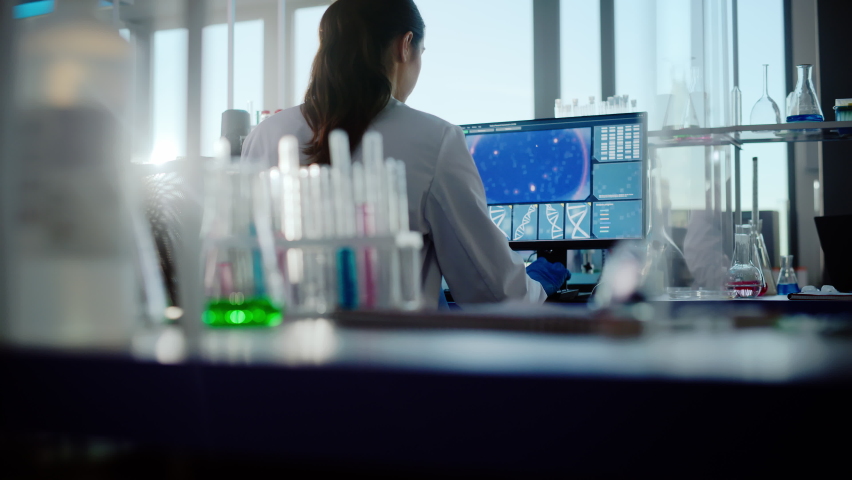 Medical Science Laboratory with Diverse Team of Professional Biotechnology Scientists Developing Drugs, Female Biochemist Working on Computer Showing Gene Therapy Interface. Back view Shot | Shutterstock HD Video #1061389489