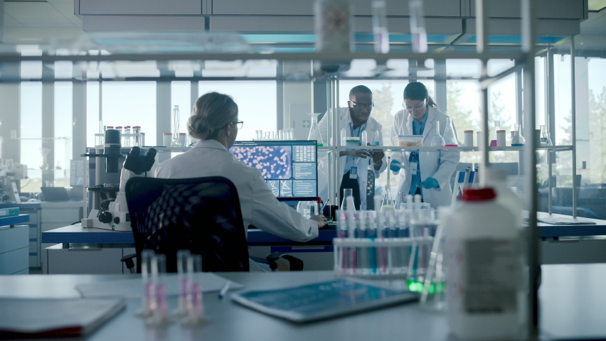 Medical Science Laboratory with Diverse Team of Professional Research Scientists Working with Microscopes, Computers. Developing Drugs, Vaccines, Gene Editing, using High-Tech Equipment. Moving Shot | Shutterstock HD Video #1061389519