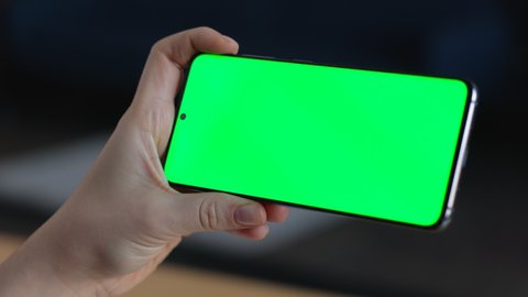 Closeup of Woman`s Hand is Holding Chroma Key Green Screen in horizontal Position without touching, swiping. Using Phone With Green Mock-up, Surfing Internet, Watching Content Videos Blogs, Apps.