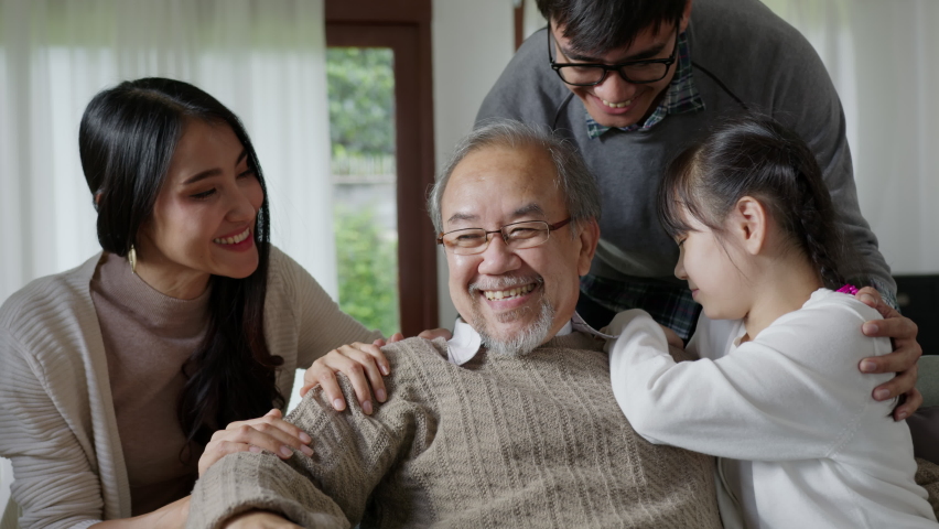 Close up candid of asian family multi generation sitting on sofa at living room. Grandfather feeling worry, lonely and depress is supported and take care by family during quarantine covid pandemic. Royalty-Free Stock Footage #1061392072