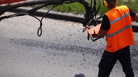 Road worker sprays hot bitumen to cover holes or cracks in the asphalt road.