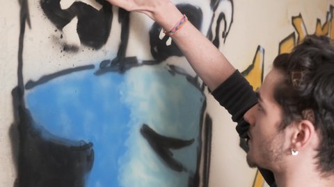 Young artist launching a graffiti message to raise awareness about keeping social distancing, prevention and use of the mask to combat the transmission of the coronavirus COVID19