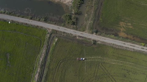 Very high pull out birds eye view of aFarmer spraying pesticides on rice field in Cambodia