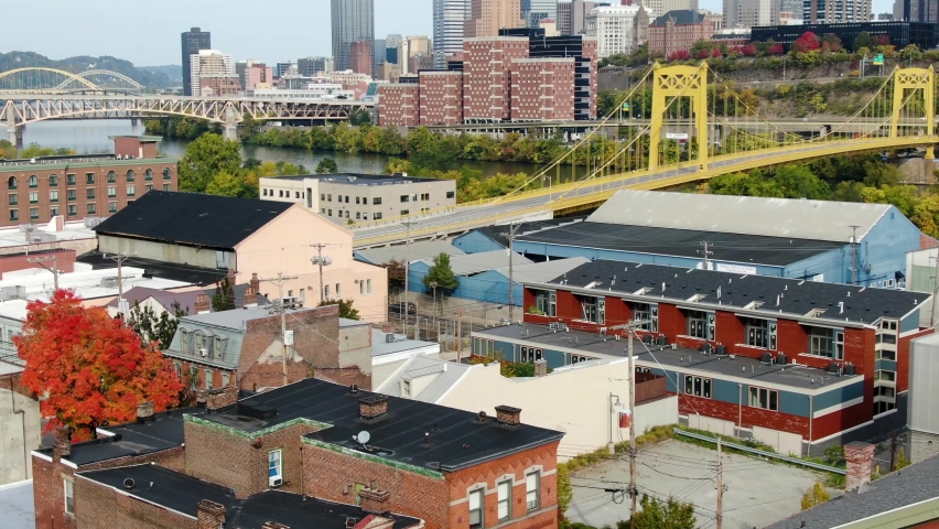 Colorful aerial in autumn of Pittsburgh, Pennsylvania, United States. Urban city skyline, yellow steel bridge, Monongahela River and downtown business district skyscrapers near residential homes.