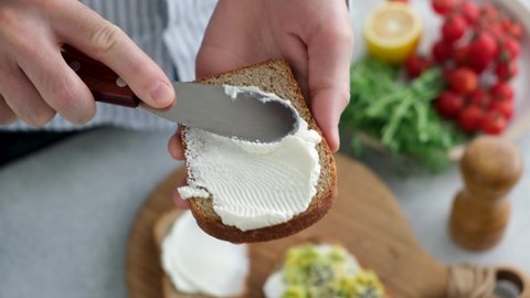 Spreading cream cheese on slice of bread. Bread and cheese toast