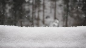 Snowfall and the snowdrift - SLOW MOTION HD VIDEO. Falling snowflakes in the woodlands. Horizontal snowdrift on the wooden handrail in the foreground. Blurred background. Half speed.
