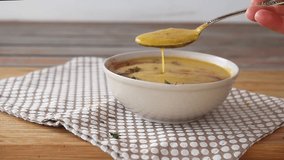 Female hands pouring pumpkin and carrot soup into a bowl using a ladle, garnished with dill and spices on top, served on a napkin on a wooden table. Traditional autumn and winter dish, warm and spicy. - Powered by Shutterstock - Get 15% off with code: PIKWIZARD15