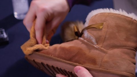 Hands cleaning men's camel suede desert shoe boot with a brush. Footwear maintenance captured from above top view.