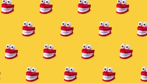 seamless looping animation of chattering teeth toys with big eyes on yellow bright background. patern of plastic red mouths with white fangs is a concept of oral hygiene and healthy teeth