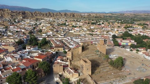 Aerial view of Guadix cityscape overlooking medieval Moorish fortified alcazaba in foreground and Roman Catholic Cathedral in background, Granada, Spain. High quality 4k footage