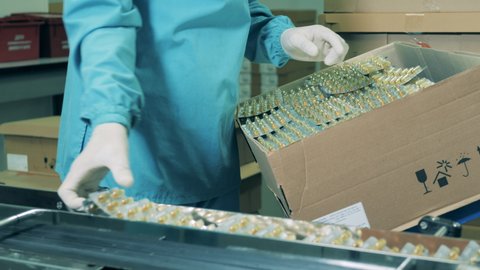 Pharmacist puts pills into a box. Pharmaceutical factory production line. Pharmaceuticals production line at a modern pharmaceutical facility.