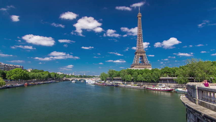 The Eiffel tower timelapse hyperlapse from Bir-Hakeim bridge over the river Seine in Paris. Ship and boats on river at sunny summer day