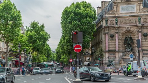 Street view of Place Saint-Michel with ancient fountain timelapse, Paris. Traffic on the road with cars and people. Cloudy sky at summer day