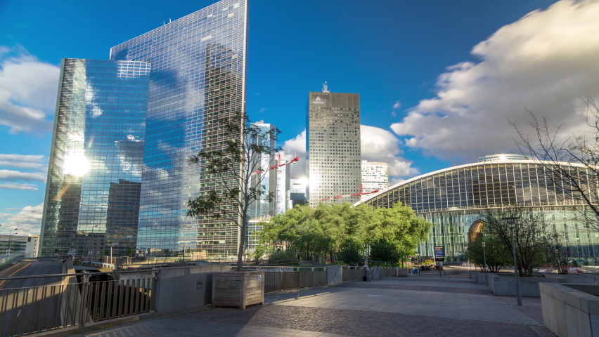 Skyscrapers of Defense timelapse hyperlapse modern business and financial district in Paris with highrise buildings and convention center. View from bridge. Blue cloudy sky in summer day. Reflections Royalty-Free Stock Footage #1061418166