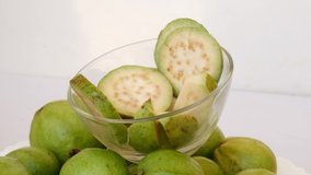 Video footage of guava pieces in glass bowl on the bunch of guavas