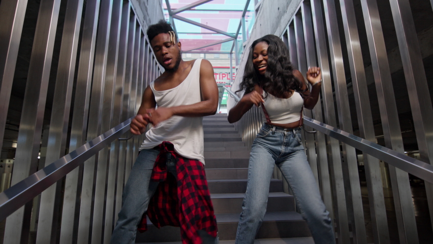 Street Dancing. Young Couple Dancing On The Stairs. Cheerful Black Guy And Girl Dancing Modern Dance. Black Guy And Girl Move Rhythmically. Cute Young People In Jeans. Stylish Guy With Beard And Girl Royalty-Free Stock Footage #1061421061