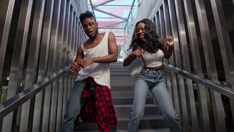 Street Dancing. Young Couple Dancing On The Stairs. Cheerful Black Guy And Girl Dancing Modern Dance. Black Guy And Girl Move Rhythmically. Cute Young People In Jeans. Stylish Guy With Beard And Girl