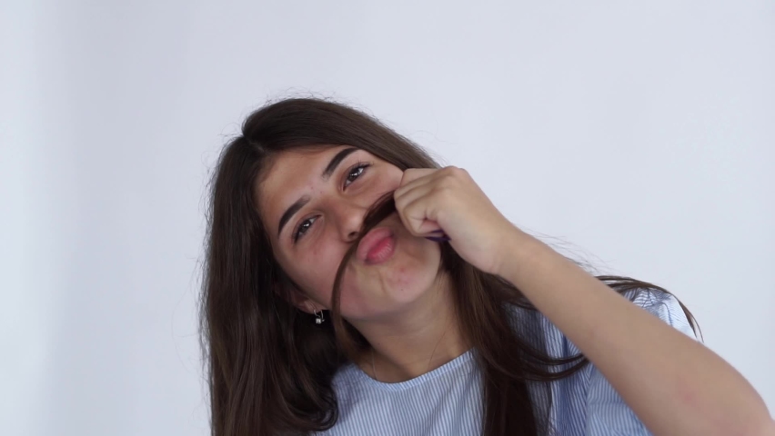 The young woman made a mustache out of her hair and pouted out her lips. Make faces. Funny cute girl