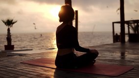 Yogi girl is sitting in lotus pose in front the sea in summer on sunset, healthy lifestyle, movement concept, meditation concept - Powered by Shutterstock - Get 15% off with code: PIKWIZARD15