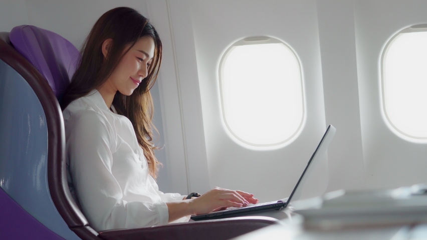 Asian young woman using laptop sitting near windows at first class on airplane during flight,Traveling and Business concept Royalty-Free Stock Footage #1061432941